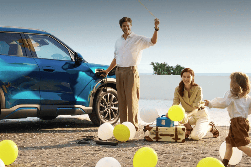 Image of family near BYD ATTO 2 DM-i car with the father plugging an appliance in to demonstrate Vehicle to Load functionality